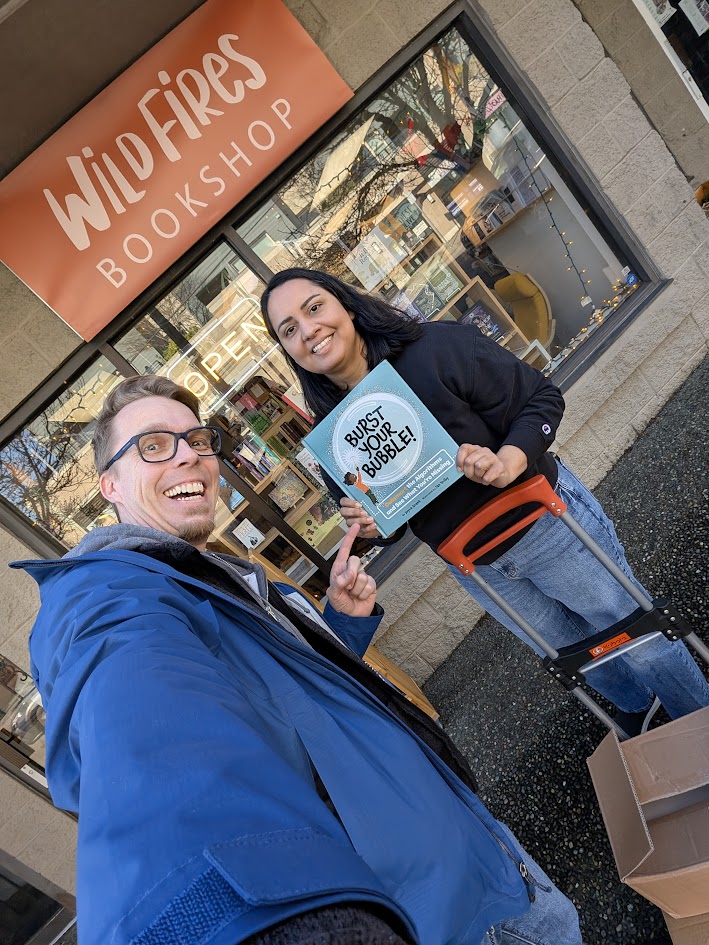 Holding up a copy of Burst Your Bubble! outside Wildfires bookshop